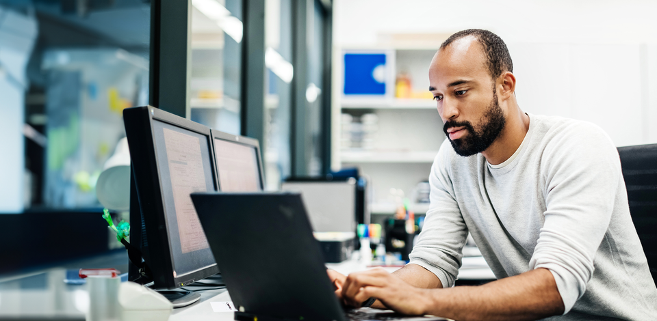 A man concentrating on his tasks of customer service while seated at a desk with a laptop